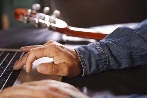 Man's hands looking for information on how to learn to play the guitar online Stock Photos