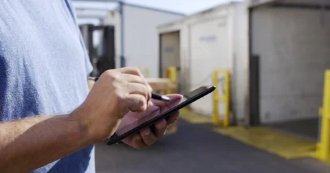 Man's hands make electronic notes while forklift loads truck 4K Stock Footage 79982300