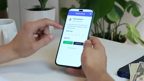 A mans hands navigate a mobile shopping app, loading a product page for sports Stock Footage 318517431