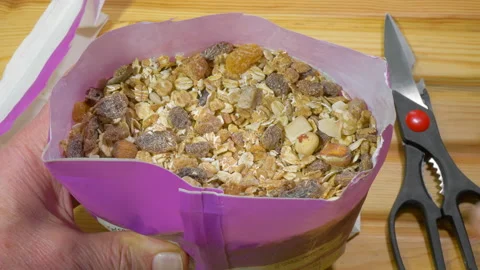 Man's hands with a newly cut open packet of muesli cereal. Video stock 170256455