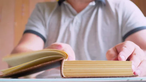 A man's hands open an old book lying on a table Stock Footage 336203365