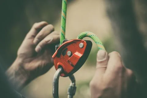 Man's hands operating a rock climbing belaying device Stock Photos