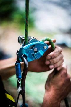 Man's hands operating a rock climbing belaying device Stock Photos