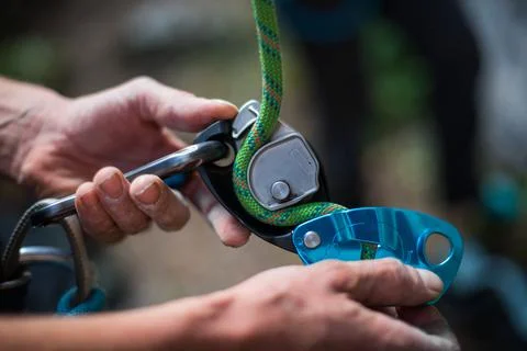 Man's hands operating a rock climbing belaying device Stock Photos