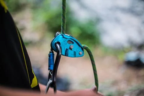 Man's hands operating a rock climbing belaying device Stock Photos