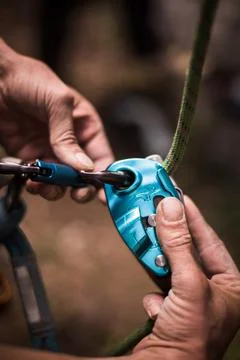 Man's hands operating a rock climbing belaying device Stock Photos