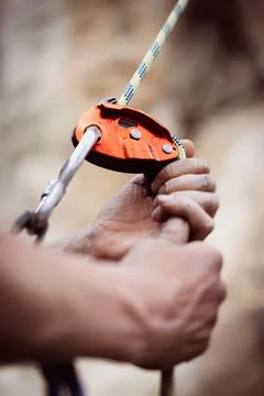 Man's hands operating a rock climbing belaying device Stock Photos