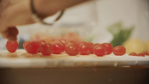 Man's hands organize mini red grape tomatoes on kitchen counter cutting board Stock Footage 99938426