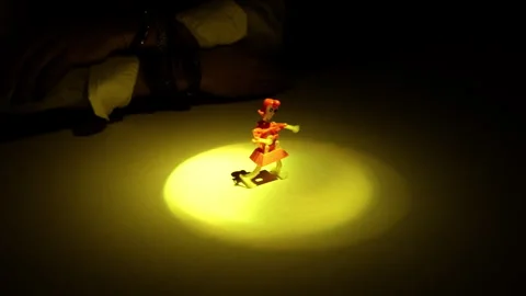 A man's hands place a mechanical puppet on a table illuminated by a beam of Stock Footage 241750000