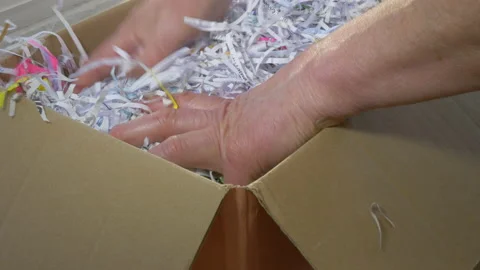 Man’s hands placing bubble wrapped package in box with shredded paper packaging. Video stock 143097077