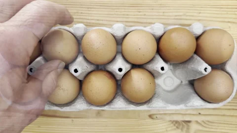 A man’s hands placing twelve hen’s eggs into a cardboard box. Stock Footage 304885223