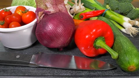 Man's hands placing vegetables on a board next to a knife, ready to chop. Video stock 159151056