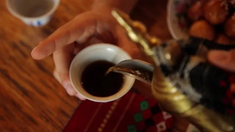 Man's hands pour some tea or coffee from arabic teapot into the cup. 스톡 동영상 201156115
