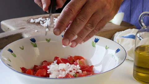 Man's hands pouring chopped spring onion into a salad bowl with tomato. Stock Footage 195950236