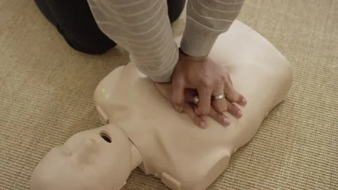 Man's hands practicing chest compression on dummy in first aid EMT training Stock Footage 168654080