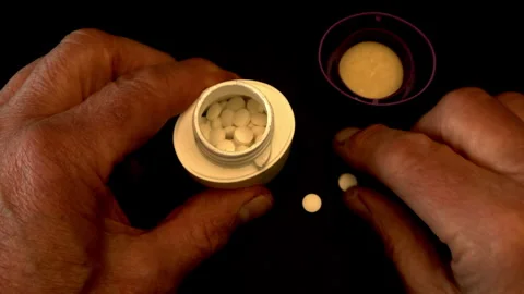 Man’s hands putting pills / tablets back into a bottle. Stock Footage 240702750