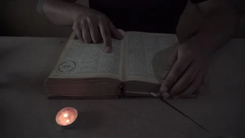 Man's hands reading and leafing through a book, candle and incense, bible Stock Footage 144414932