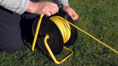 Man’s hands reeling in a power cable on a rotating drum. Stock-Footage 129223518