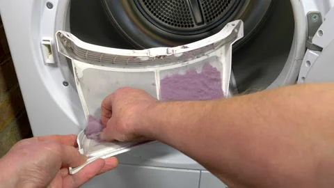 A man's hands removing the lint / fluff from a tumble dryer filter. Stock Footage 167279328