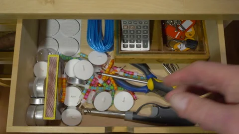 Man's hands removing a screwdriver from a drawer of miscellaneous items. Video stock 166619701