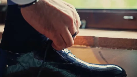 Man's hands with rings tie up an elegant shoe. Stock Footage 228950344