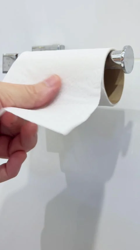 Mans hands rolling down toilet paper from a wall mounted toilet paper roll Stock Footage 306008134