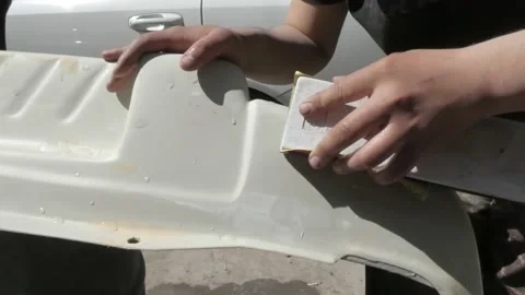 The man's hands rub and grind the surface of a car part. Stock Footage 152974803