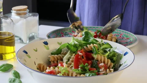 Man's hands serving a pasta salad on a plate with a salad spoons. Stock Footage 195951185