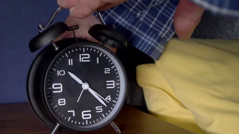 Man's hands setting an alarm clock on a table next to a bed. Stock Footage 200875193