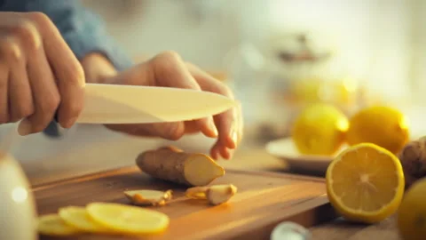 A mans hands skillfully chop fresh ginger root on a wooden cutting board sur Stock Footage 331314539