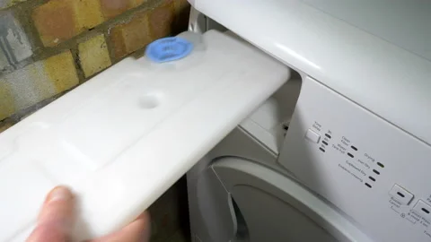 A man's hands sliding out a full waste water tank from a tumble dryer. Stock Footage 167279223