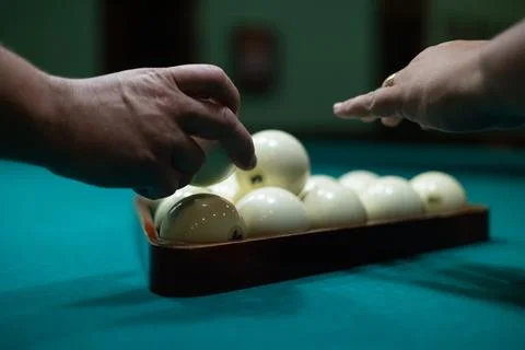 A man's hands stack billiard balls into a pyramid on a billiard table. A man Stock Photos
