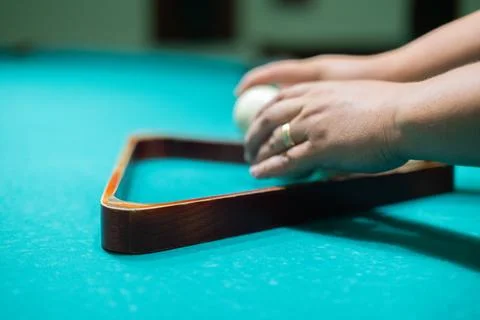 A man's hands stack billiard balls into a pyramid on a billiard table. A man Stock Photos