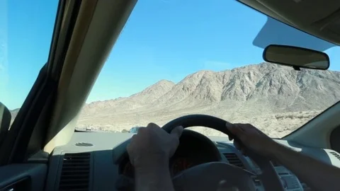 Man's hands on the steering wheel as he drives by mountains. Stock Footage 81596488