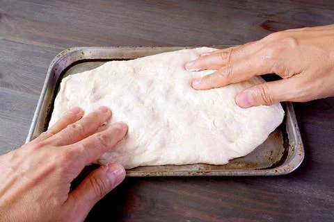 Man's hands stretching risen dough in a pan for baking pizza or bread 스톡 사진