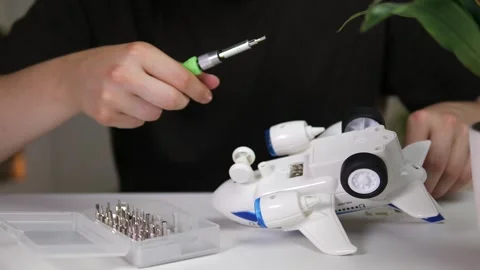 A mans hands at a table carefully insert batteries into a toy airplane using a Stock Footage 318721230