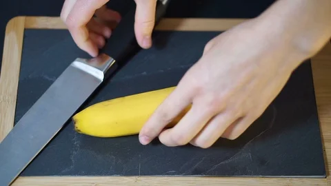 Man's hands take a knife and cut the Banana exactly in half Stock Footage 106760401