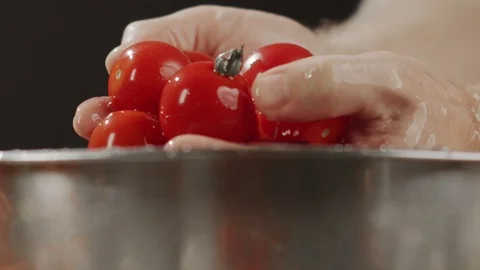 Man's hands take out cherry tomatoes washed in water from metal bowl Stock Footage 123960325