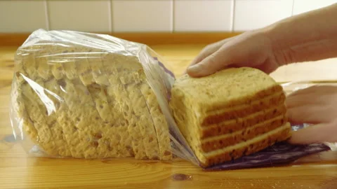 A man's hands taking slices of grain and seed bread from a packet. Stock Footage 252490831