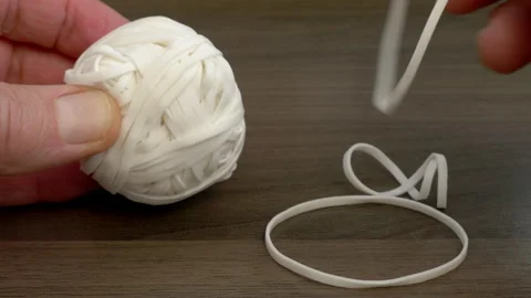 A man's hands taking some rubber bands from a ball. Vídeos de archivo 251649931