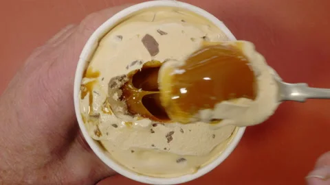 Man’s hands taking a spoonful of caramel ice cream from a fresh tub. Vídeos de archivo 221275875