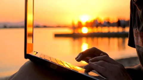 Mans hands tapping on notebook on sunset background. Freelancer working on the Stock Footage 116297458