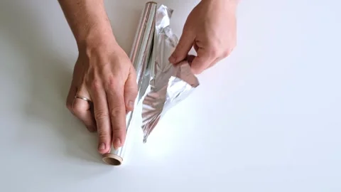 The mans hands tear off a piece of foil from a roll on white background close-up Stock Footage 323110522