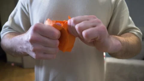 Man's hands tearing a sheet of orange cardboard. Tearing an A4 sheet of paper Stock Footage 340209153