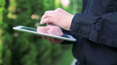 Man's hands touching and using tablet on green tree background Stock-Footage 64718320