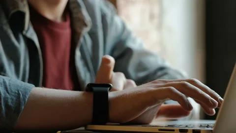 Man's hands typing on laptop keyboard, using smart watch Stock Footage 166393196