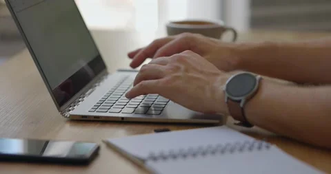 Man's hands typing on laptop while drinking coffee or tea.Guy using paper Stock Footage 160770788
