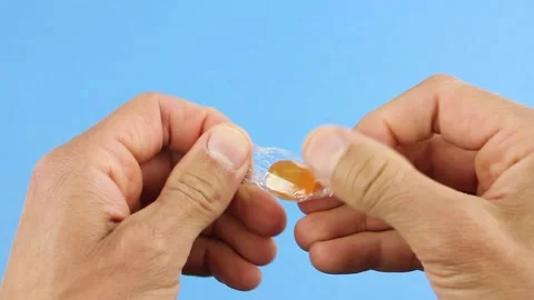 Mans hands unfold one orange candy lollipop from to release stress Stockbeeldmateriaal 156474683