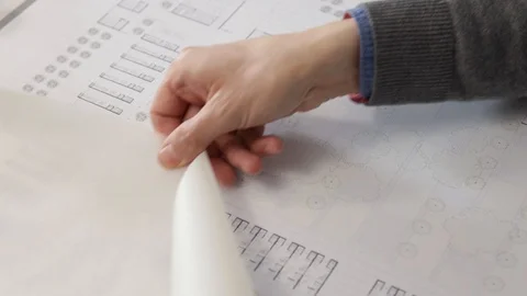 Man's hands unrolling tracing paper over a blueprint Stock Footage 125873128