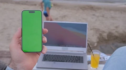 Man's hands use smartphone with laptop, money dollars on the beach closeup, top Stock Footage 246031531